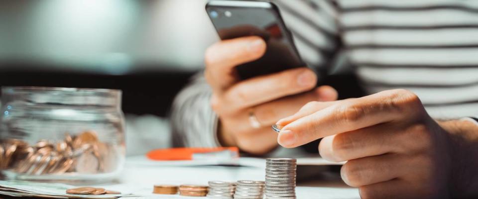 Close up on hands holding cell phone and stacking change