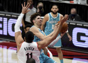 Charlotte Hornets guard LaMelo Ball, center, drives to the basket on Portland Trail Blazers center Enes Kanter, right, during the first half of an NBA basketball game in Portland, Ore., Monday, March 1, 2021. (AP Photo/Steve Dykes)