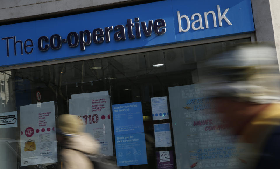 Pedestrians walk past a branch of the Co-operative Bank in London, Monday, Feb. 13, 2017. Britain's Co-operative Bank is putting itself up for sale as it struggles to meet capital requirements designed to ensure financial institutions can survive hard times. (AP Photo/Alastair Grant)
