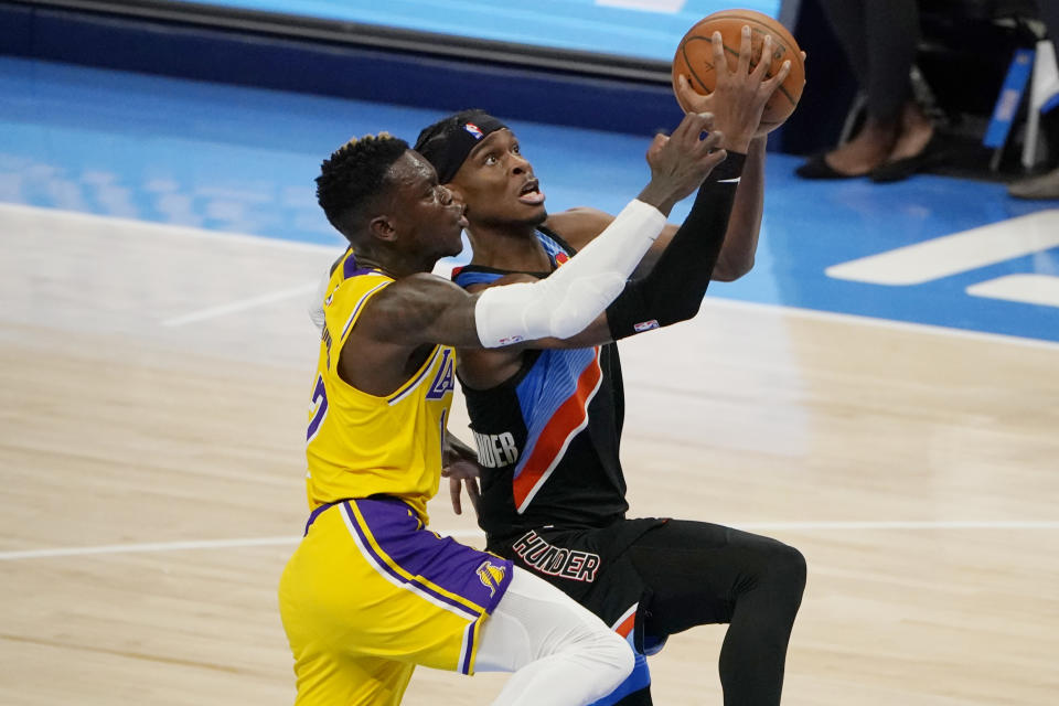 Oklahoma City Thunder guard Shai Gilgeous-Alexander, right, goes to the basket while defended by Los Angeles Lakers guard Dennis Schroeder during the first half of an NBA basketball game Wednesday, Jan. 13, 2021, in Oklahoma City. (AP Photo/Sue Ogrocki)