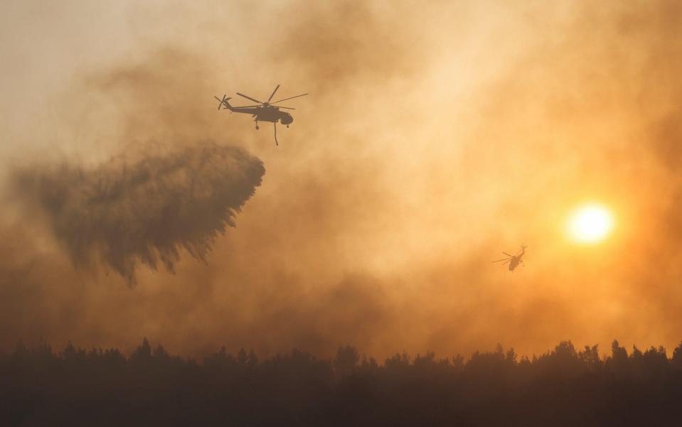 A firefighting helicopter makes a water drop as a wildfire continues to rage at Varympompi suburb north of Athens - REUTERS