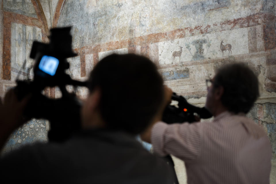 Journalists look at the frescoes coming from the sacellum, a small votive chapel, of a two-story home, or "Domus," dating from around 134-138 AD that was partially destroyed to make way for the construction of the Caracalla public baths, which opened in 216 AD, are on display at the Caracalla archaeological park in Rome, Thursday, June 23, 2022. The frescoed ceiling and walls of a domestic temple honoring Greco-Roman and Egyptian religious deities and believed to have belonged to a wealthy merchant family were first discovered in the mid-19th century about 10 meters (yards) underneath the current ground level of the baths, had been briefly exhibited but has been closed to the public for 30 years. (AP Photo/Domenico Stinellis)