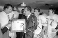 FILE - In this Dec. 6, 1969, file photo, President Richard Nixon presents a plaque to Texas football coach Darrell Royal, naming the Longhorns the No. 1 college football team in college football as linebacker Glen Halsell (67) and quarterback James Street (16) watch. The Longhorns' fourth-quarter comeback led by Street erased Arkansas' 14-0 lead and sent Texas unbeaten into the Cotton Bowl, but it wasn't even the memorable part of the event for many who remember it. Nixon arrived by helicopter to attend the game, and after he declared the Longhorns national champions —- before they even played their bowl game. (AP Photo/File)