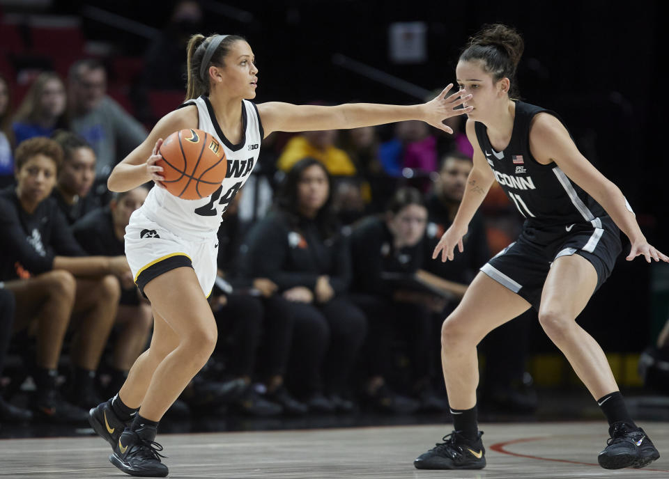 Iowa guard Gabbie Marshall, left, dribbles towards UConn forward Lou Lopez-Senechal during the first half of an NCAA college basketball game in the Phil Knight Legacy Championship in Portland, Ore., Sunday, Nov. 27, 2022. (AP Photo/Craig Mitchelldyer)