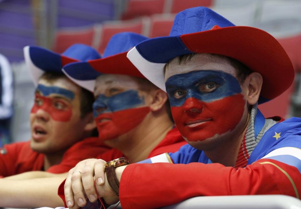 Fans with their faces painted in the colours of the Russian flag look on before the men's preliminary round ice hockey game between Russia and USA at the Sochi 2014 Winter Olympic Games February 15, 2014. REUTERS/Jim Young (RUSSIA - Tags: SPORT ICE HOCKEY OLYMPICS)