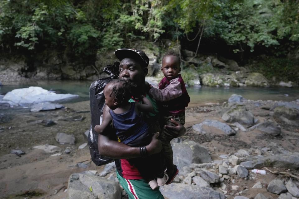 Un migrante lleva a dos niños a través de un río el miércoles 15 de septiembre de 2021 con rumbo norte, cerca de Acandí, Colombia. (AP Foto/Fernando Vergara)