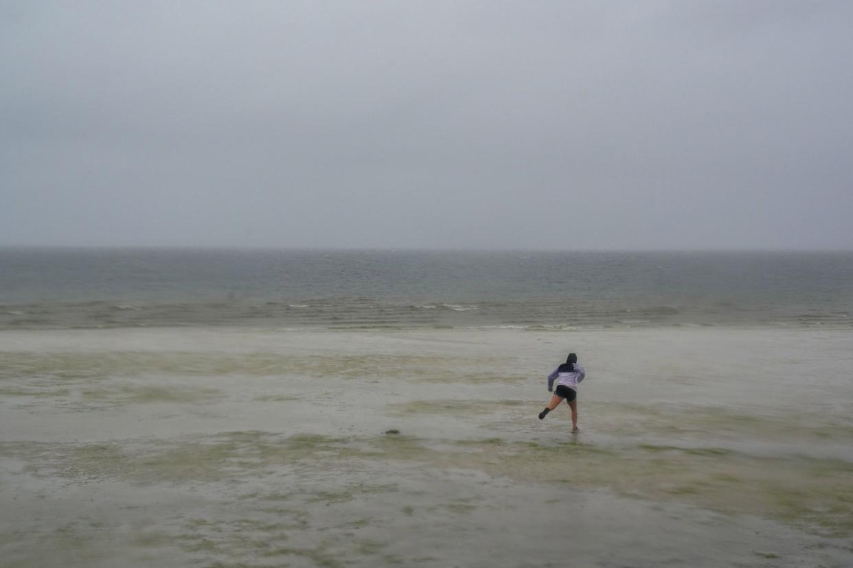 A woman walks in the Bay as the tide recedes from Tampa Bay as Hurricane Ian approaches on Sept. 28, 2022, in Tampa, Fla. Ian intensified to just shy of catastrophic Category 5 strength Wednesday as its heavy winds began pummelling Florida, with forecasters warning of life-threatening storm surges after leaving millions without power in Cuba.