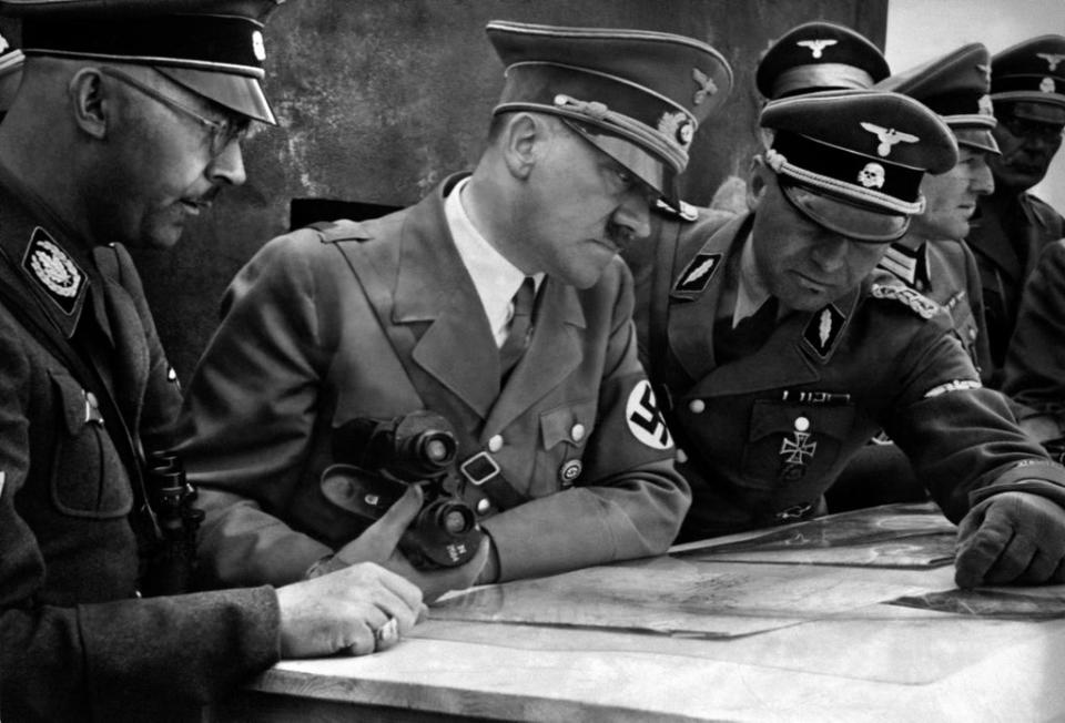 A picture dated 1939 shows German Nazi Chancellor and dictator Adolf Hitler (C) consulting a geographical survey map with his general staff including Heinrich Himmler (L) and Martin Bormann (R) at an unlocated place during World War II (AFP via Getty Images)