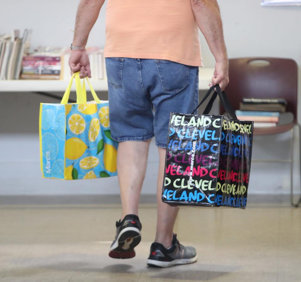 A shopper heads for the door with totes full of books after shopping at the Friends of Rodman Public Library's annual Used Book Sale on Saturday, Aug. 5, 2023, at The Commons on South Linden Avenue in Alliance.