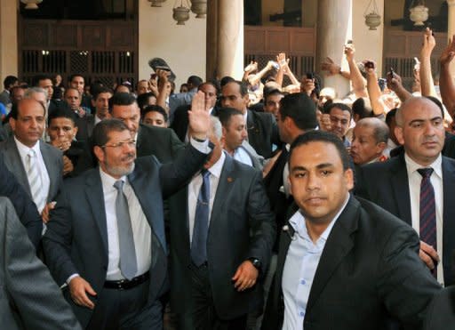 In this handout picture made available by the Egyptian presidency, president-elect Mohamed Morsi (left) waves to supporters after the weekly prayers at Cairo's historic Al-Azhar mosque on the eve of his swearing-in as Egypt's first civilian president