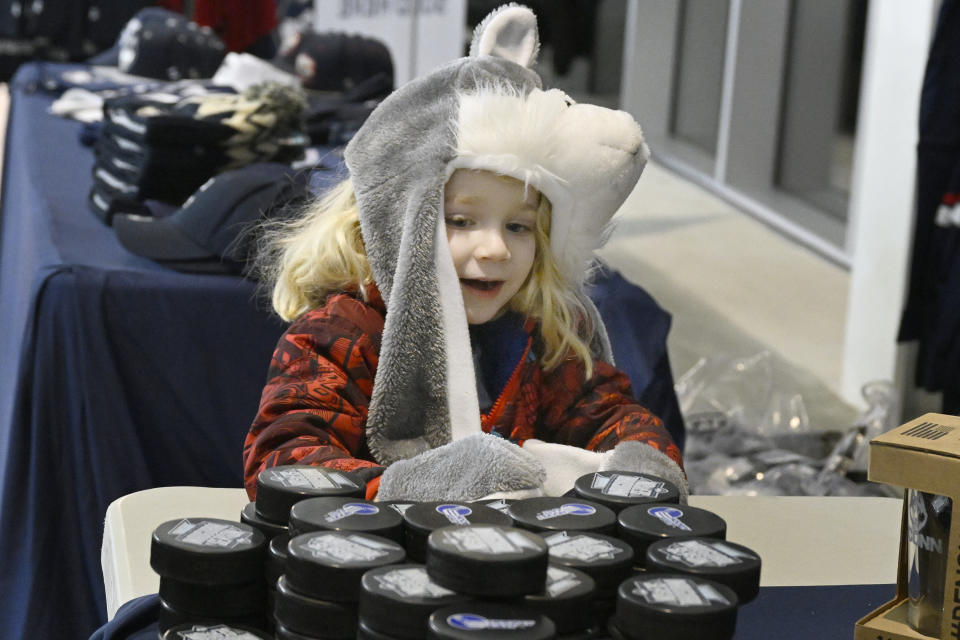 Parker Heilbrunn of West Hartford eyes hockey pucks on a vendor table during an NCAA college hockey game between UConn and Merrimack Friday, Jan. 13, 2023, at the Toscano Family Ice Forum in Storrs, Conn. (AP Photo/Jessica Hill)