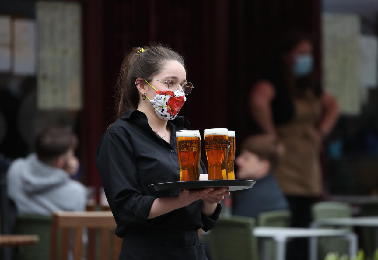 A server carries a tray of drinks from a pub in the Grassmarket in Edinburgh, as beer gardens, non-essential shops, restaurants and cafes, along with swimming pools, libraries and museums in Scotland reopen today after lockdown restrictions have eased. Picture date: Monday April 26, 2021. (Photo by Andrew Milligan/PA Images via Getty Images)