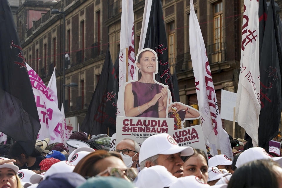 FILE - A cutout poster of ruling party presidential candidate Claudia Sheinbaum towers over supporters during her opening campaign rally at the Zocalo in Mexico City, March 1, 2024. Mexican voters will go to the polls in the largest elections in the country’s history on June 2, 2024. In the presidential race, they will have to choose between three candidates, but two women have taken the lead: Sheinbaum and opposition candidate Xóchitl Gálvez. (AP Photo/Aurea Del Rosario, File)
