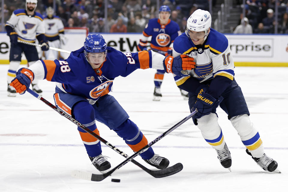 New York Islanders defenseman Alexander Romanov (28) and St. Louis Blues center Brayden Schenn vie for the puck during the first period of an NHL hockey game Tuesday, Dec. 6, 2022, in Elmont, N.Y. (AP Photo/Adam Hunger)