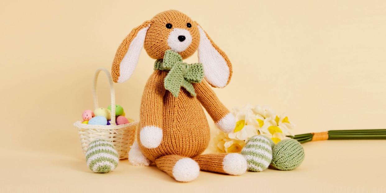 knitted easter bunny and easter eggs on yellow background
