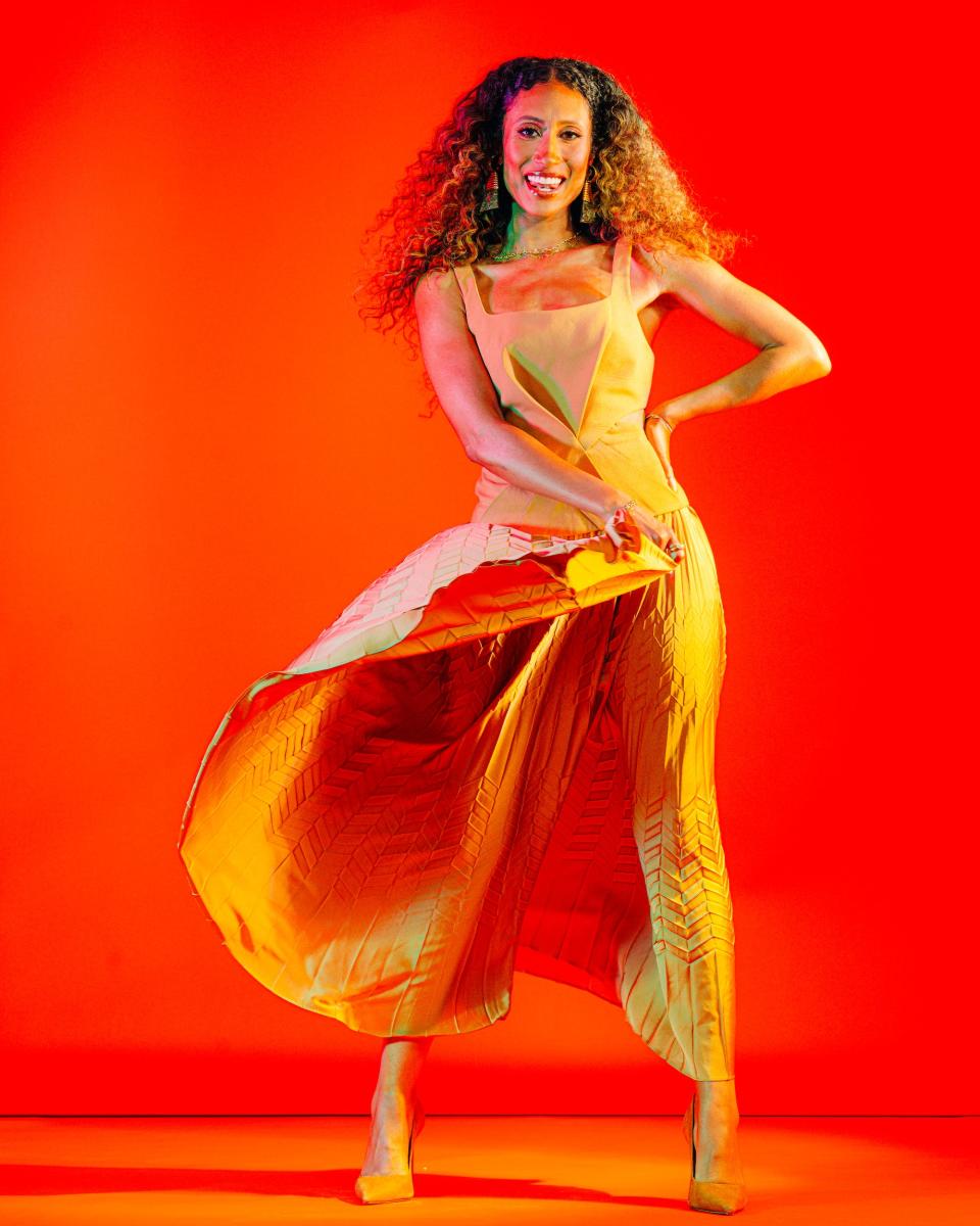 Elaine Welteroth full body portrait, billowing orange skirt against bright red studio background