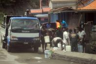 Local residents fill containers of water after a series of eruptions from La Soufriere volcano