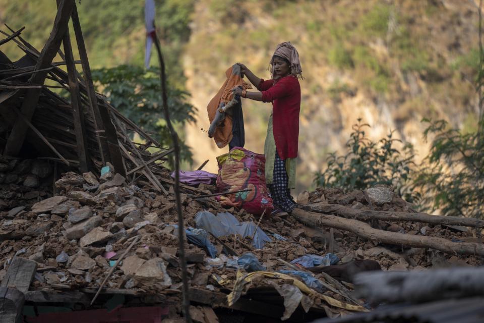 A survivor recovers winter clothes from an earthquake damaged house in Rukum District, northwestern Nepal, Monday, Nov. 6, 2023. The Friday night earthquake in the mountains of northwest Nepal killed more than 150 people and left thousands homeless. (AP Photo/Niranjan Shrestha)