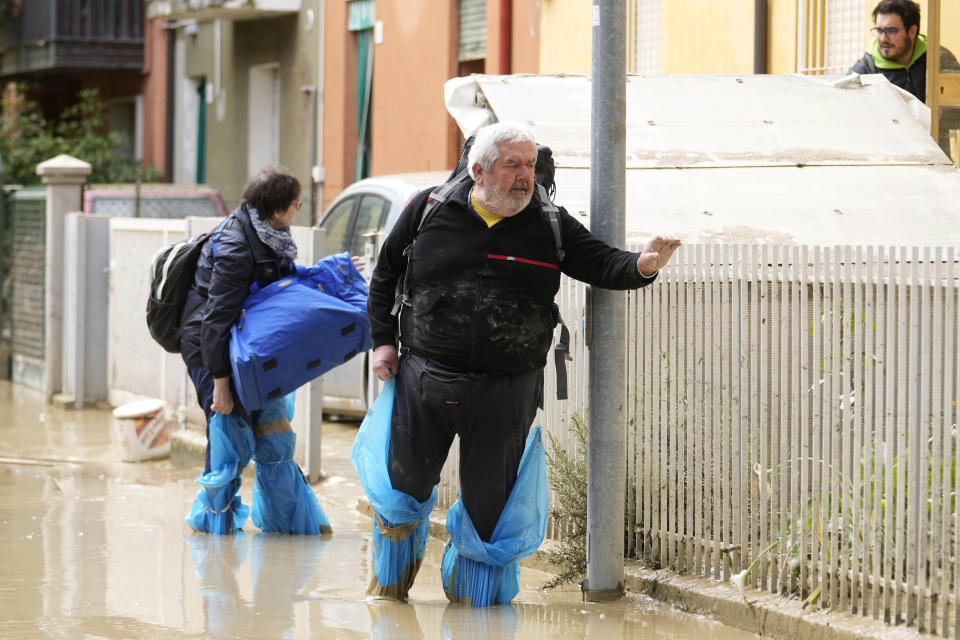 People walk in a flooded road in Faenza, Italy, Thursday, May 18, 2023. Exceptional rains Wednesday in a drought-struck region of northern Italy swelled rivers over their banks, killing at least eight people, forcing the evacuation of thousands and prompting officials to warn that Italy needs a national plan to combat climate change-induced flooding. (AP Photo/Luca Bruno)