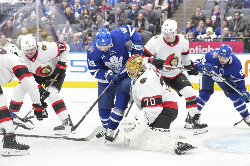 Toronto Maple Leafs' Calle Jarnkrok (19) tries to dig the puck out in front of Ottawa Senators goaltender Joonas Korpisalo (70) during the second period of an NHL hockey match in Toronto, on Wednesday, Nov. 8, 2023. (Chris Young/The Canadian Press via AP)