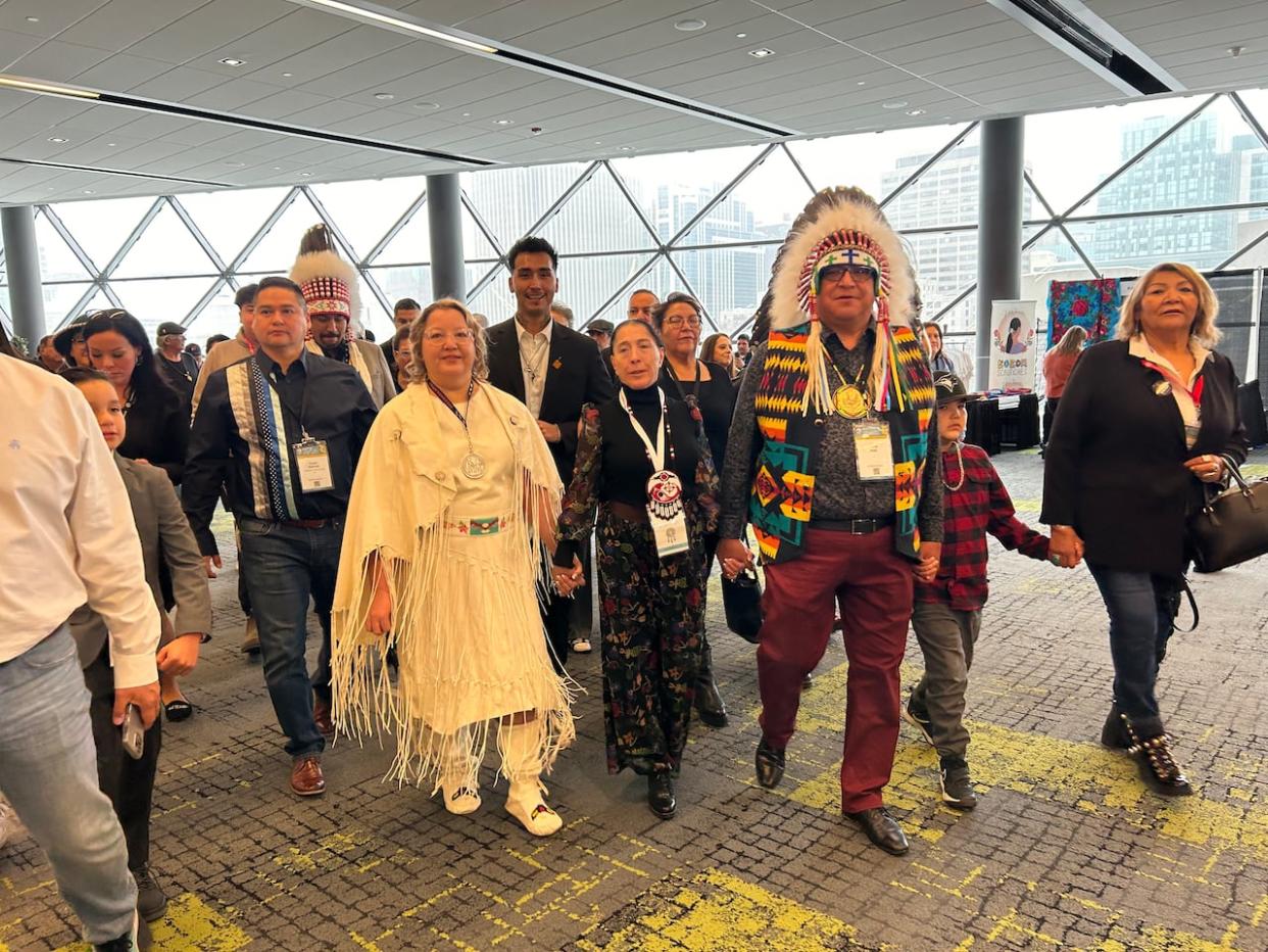 New AFN national chief-elect Cindy Woodhouse, left, holds hands with interim National Chief Joanna Bernard and national chief candidate David Pratt at the Shaw Centre in Ottawa Thursday.  (Olivia Stefanovich/CBC - image credit)