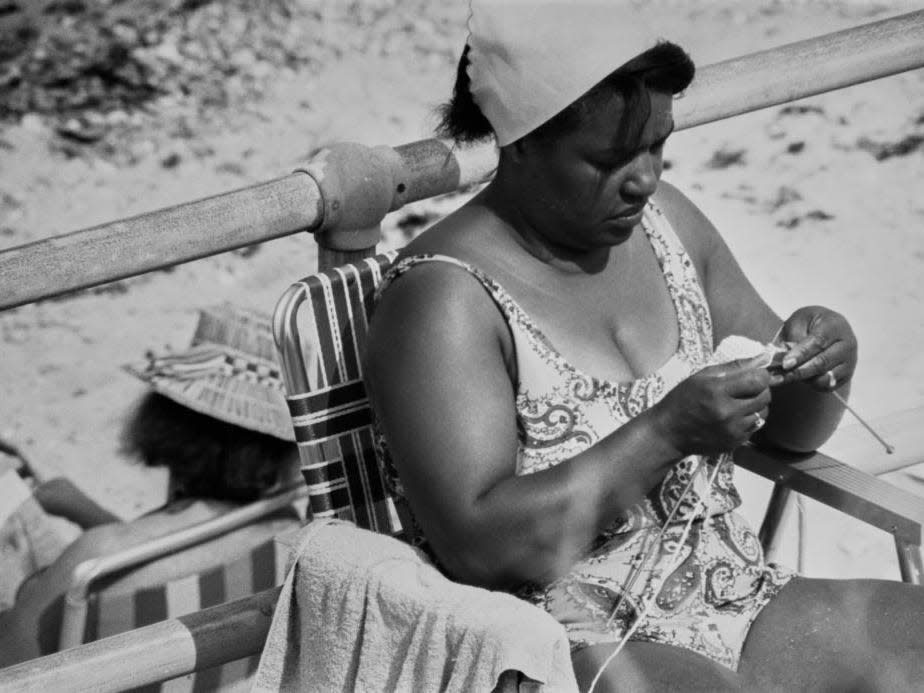 A woman wearing a swimsuit knitting as she sits on a deckchair in Martha's Vineyard