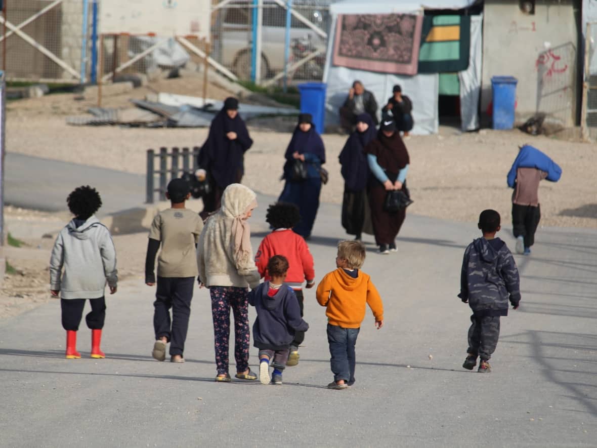 Women walk with their children in the al-Roj detention camp where a Canadian woman now in Alberta was held with her young daughter. (Stephanie Jenzer/CBC - image credit)