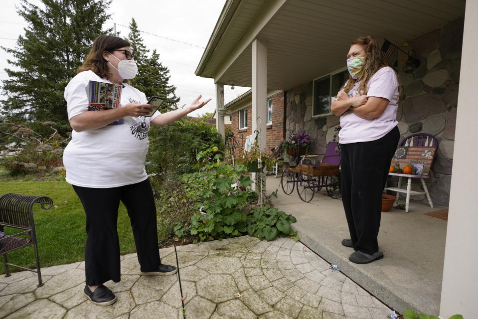 FILE - In this Thursday, Oct. 15, 2020 file photo, Lori Goldman talks with a voter while canvassing in Troy, Mich. In suburban Michigan, a coalition of suburban women achieved what they set out to do _ help evict Donald Trump from the White House. But Goldman, who runs the group Fems for Dems, can’t shake the sense that their mission now is more critical than it’s ever been. “We got rid of this blight, this cancer,” said Goldman, 61. “We cut him out. But we know that cancer has spread, it’s spread to soft tissue, other organs. And now we have to save the rest of the body.” (AP Photo/Paul Sancya)
