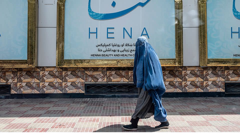 An Afghan burqa-clad woman walks past a beauty salon. Under Taliban rule, opportunities for Afghan women and girls have been severely restricted. - Wakil Kohsar/AFP/Getty Images