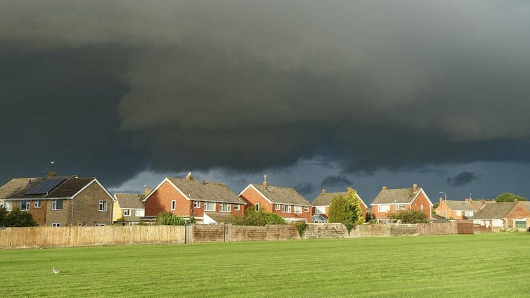 Dark gray storm clouds gather above houses in a village.