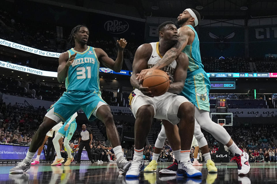 New Orleans Pelicans forward Zion Williamson is fouled by Charlotte Hornets forward Miles Bridges and center Nathan Mensah (31) looks on during the first half of an NBA basketball game Friday, Dec. 15, 2023, in Charlotte, N.C. (AP Photo/Chris Carlson)
