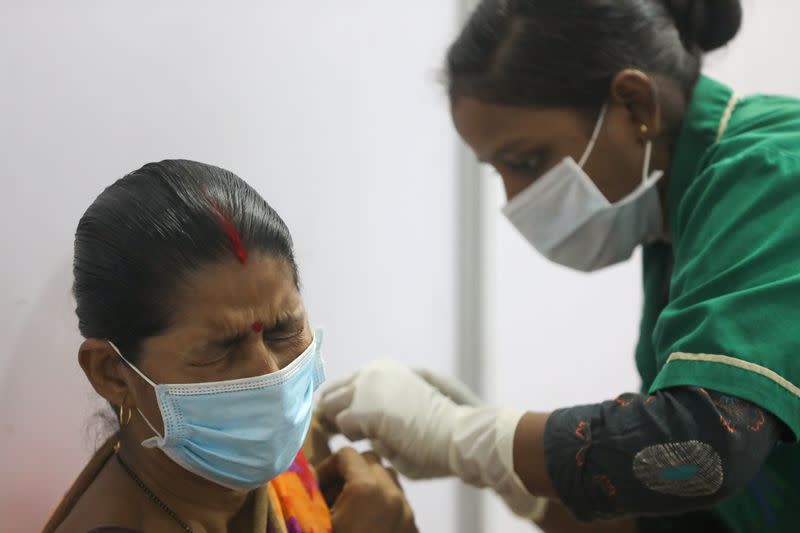 FILE PHOTO: A woman reacts as she receives a dose of COVISHIELD, a COVID-19 vaccine manufactured by Serum Institute of India, in Mumbai