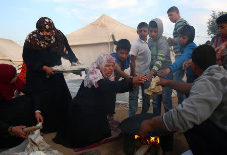 Women bake bread at a tent city protest where Palestinians demand the right to return to their homeland at the Israel-Gaza border, in the southern Gaza Strip April 11, 2018. REUTERS/Samar Abo Elouf