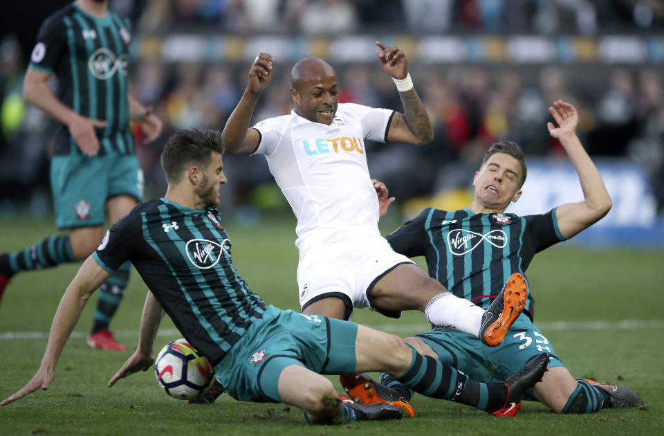 Swansea City’s Andre Ayew battles for the ball with Southampton’s Jan Bednarek, right, and Wesley Hoedt during the English Premier League soccer match at the Liberty Stadium, Swansea, Wales, Tuesday May 8, 2018. (Nick Potts/PA via AP)