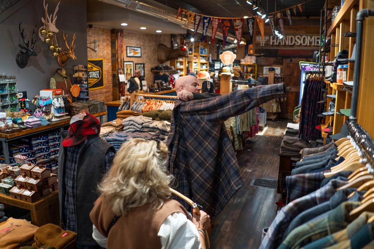 Brian Moffett of Fenton tries on a jacket while shopping with Lydia Sanchez-Roat of Saginaw at Bridge Street Exchange in Fenton on Wednesday, November 15, 2023.