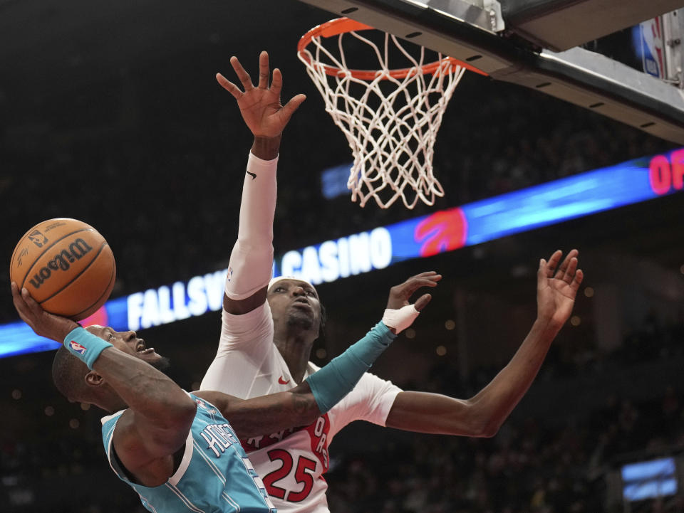 Charlotte Hornets guard Terry Rozier (3) goes up to the net under pressure from Toronto Raptors forward Chris Boucher (25) during first half of an NBA basketball game in Toronto, Monday, Dec. 18, 2023. (Nathan Denette/The Canadian Press via AP)