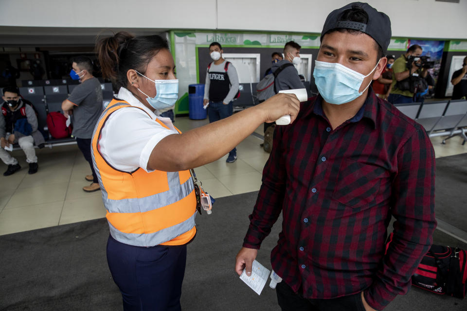 Passengers have their temperature measured before boarding a humanitarian flight to Canada at the La Aurora international airport in Guatemala City, Thursday, Sept. 17, 2020. Authorities are preparing for the reopening of the airport on Friday as part of the gradual reopening of the country's borders by allowing national flights and some duly authorized international flights. (AP Photo/Moises Castillo)