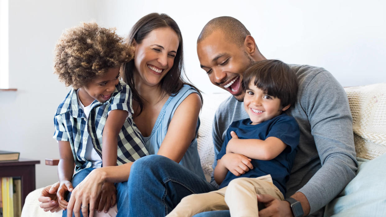 Happy multiethnic family sitting on sofa laughing together.