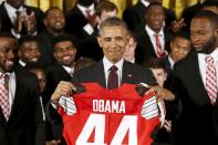 U.S. President Barack Obama receives a commemorative jersey from Ohio State team captains Doran Grant (L) and Curtis Grant (R) as he plays host to the reigning NCAA football champion Buckeyes at a reception in the East Room of the White House in Washington April 20, 2015. REUTERS/Jonathan Ernst