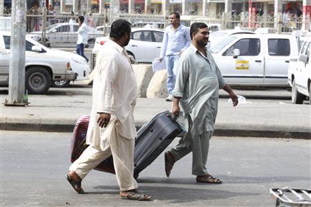 Foreign workers pull their luggage along a street in Riyadh November 4, 2013. REUTERS/Faisal Al Nasser