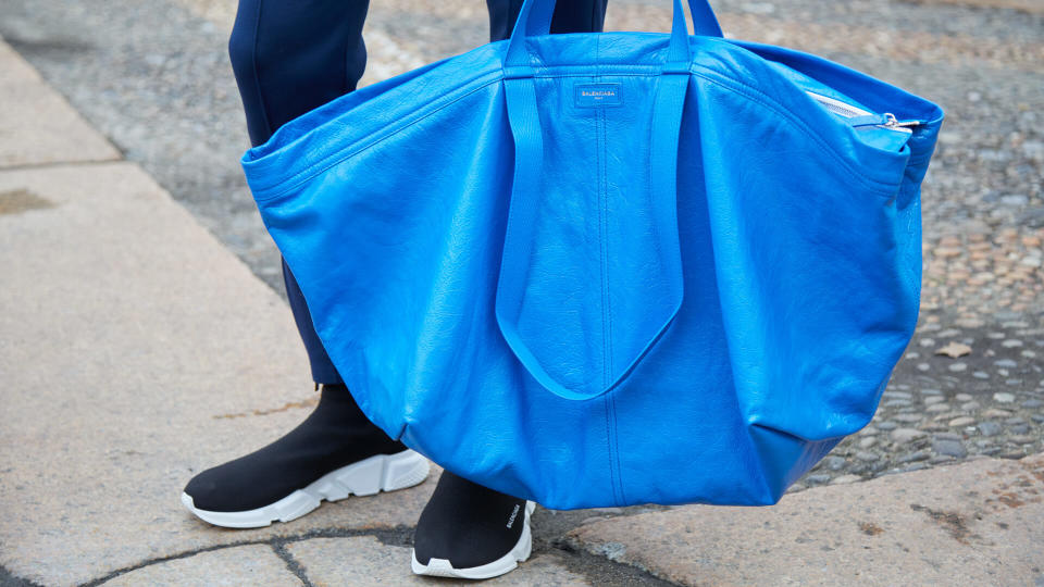 MILAN - FEBRUARY 24: Man with blue Balenciaga leather bag and black shoes before Tod's fashion show, Milan Fashion Week street style on February 24, 2017 in Milan.