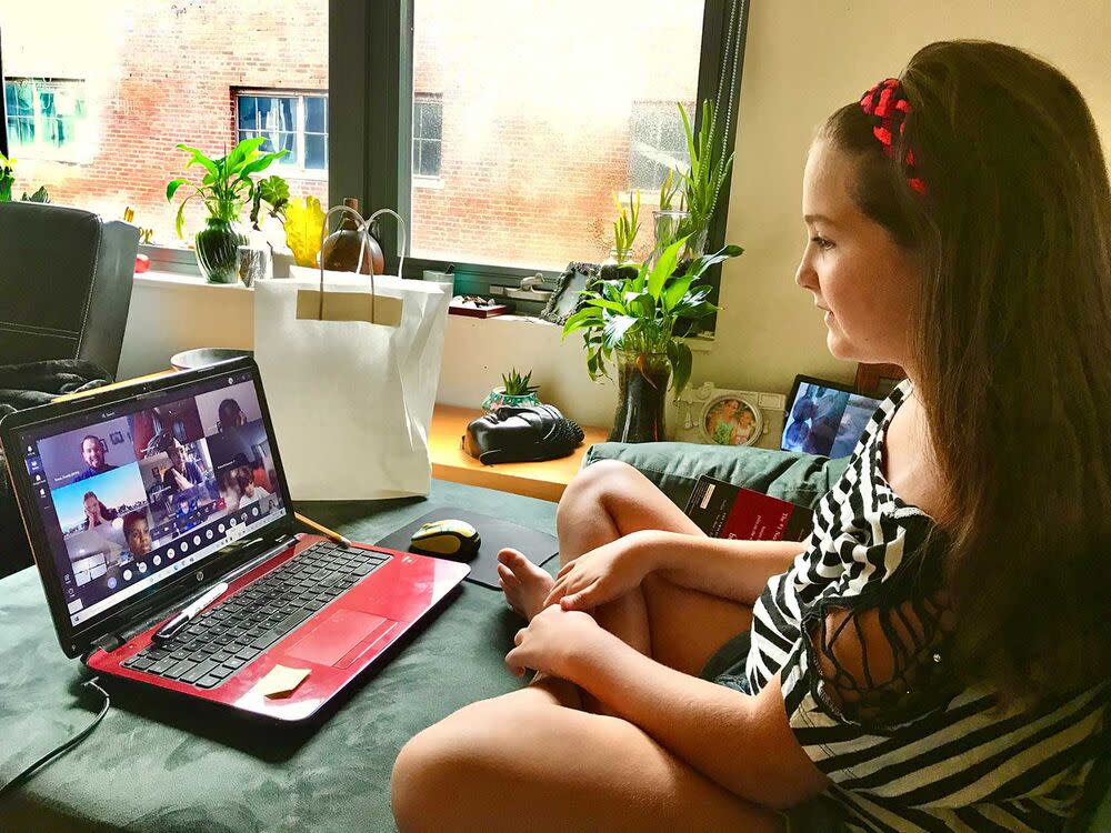 A young girl sits at a laptop.