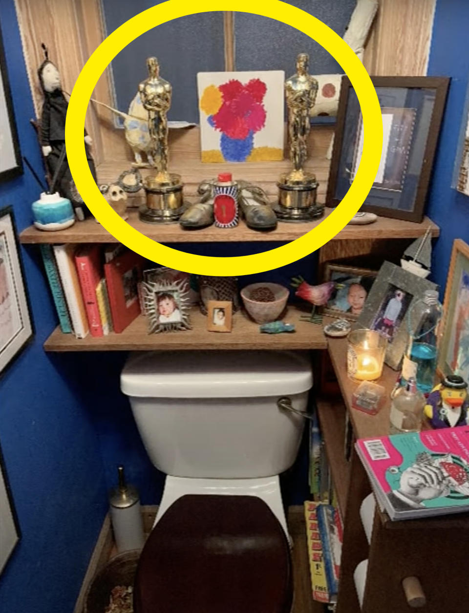 Emma's two Oscars statues on a shelf behind a toilet