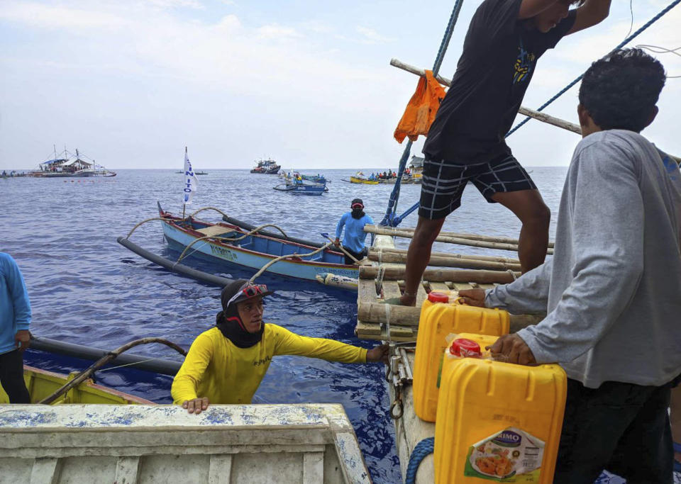 In this photo provided by Atin-Ito/Akbayan Party, activists and crew members distribute fuel to fishermen as groups from a nongovernment coalition called Atin Ito, Tagalog for This is Ours, sailed at the South China Sea on Wednesday May 15, 2024. About 100 Filipino activists on wooden boats have decided not to sail closer to a fiercely disputed shoal in the South China Sea on Thursday to avoid a confrontation with dozens of Chinese coast guard and suspected militia ships guarding the area. (Atin-Ito/Akbayan Party via AP)
