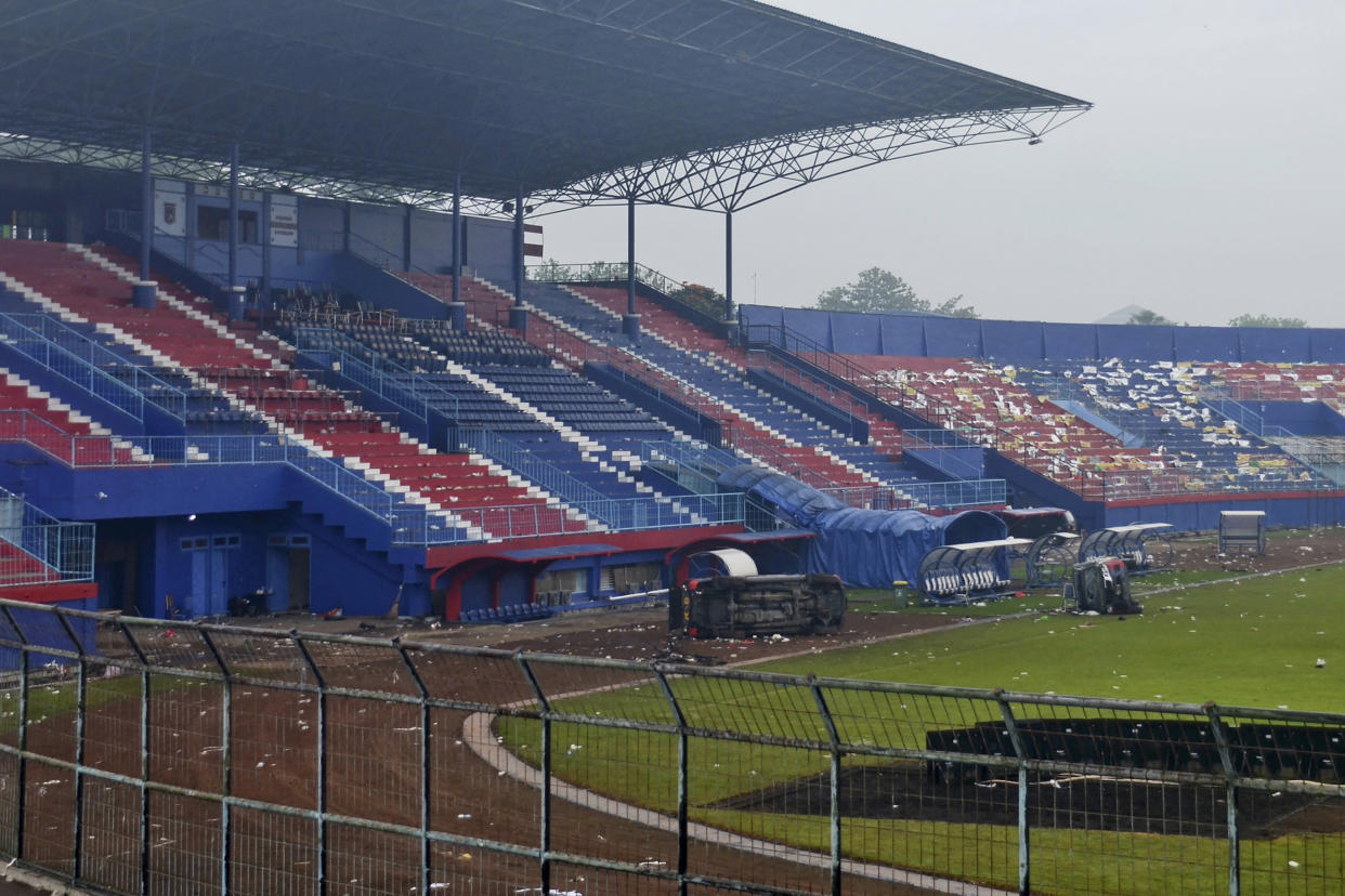 Overturned police vehicles sit on the pitch in the aftermath of a deadly soccer match stampede at Kanjuruhan Stadium in Malang, East Java, Indonesia, Sunday, Oct. 2, 2022. Panic at an Indonesian soccer match after police fired tear gas to to disperse supporters invading the pitch left over 100 people dead, mostly trampled to death, police said Sunday. (AP Photo/Hendra Permana)