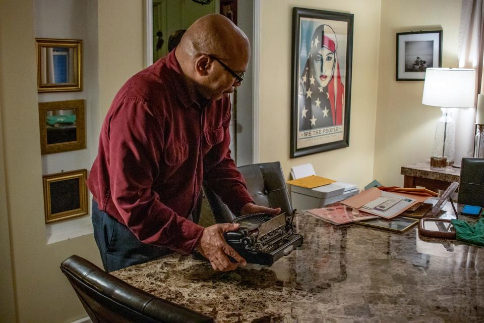 Frank McGhee, 59, moves a typewriter in February at his home in Detroit. The McGhees lost many mementos and other items of personal value as well as faced damage to their water heater, washer and dryer due to flooding.