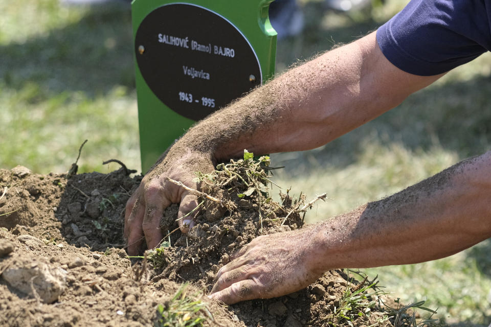 Bahrudin Salihovic gets his hands in the dirt during his father's burial in Potocari, near Srebrenica, Bosnia, Saturday, July 11, 2020. Mourners converged on the eastern Bosnian town of Srebrenica for the 25th anniversary of the country's worst carnage during the 1992-95 war and the only crime in Europe since World War II that has been declared a genocide. (AP Photo/Kemal Softic)