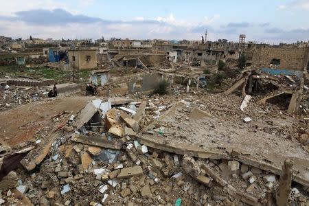 Civilians ride on a motorcycle past damaged buildings in the rebel held historic southern town of Bosra al-Sham, Deraa, Syria February 23, 2016. REUTERS/Alaa Al-Faqir