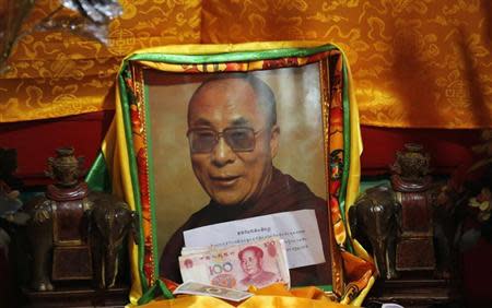 Chinese bank notes from faithful are placed in front of a portrait of Tibetan spiritual leader Dalai Lama at Kumbum monastery, where Dalai Lama used to live, on the outskirts of Xining, Qinghai province, July 6, 2013. REUTERS/Kim Kyung-Hoon