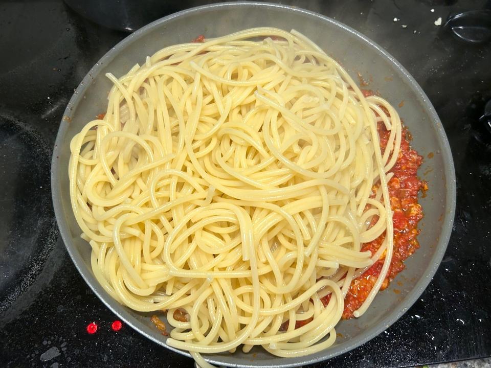Adding pasta to the sauce for Giada De Laurentiis' Bucatini All'Amatriciana pasta